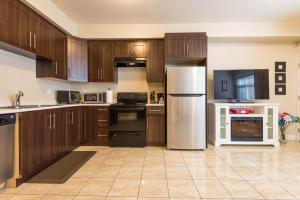 Beach Breeze White Rock في وايت روك: مطبخ مع خزائن خشبية وأجهزة من الفولاذ المقاوم للصدأ