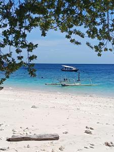 a boat in the water on a beach at Kampung Meno Bungalows in Gili Meno