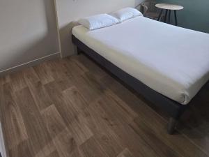 a bedroom with a bed with white sheets and a wooden floor at ibis budget Goussainville Charles de Gaulle in Goussainville