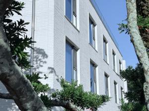 a white building with trees in front of it at 제주 신성의 숲 웰니스 호텔 in Haean