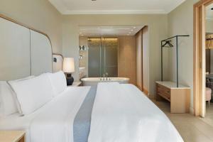a bedroom with a large white bed and a bath tub at The Westin Resort, Costa Navarino in Romanós +212 photos