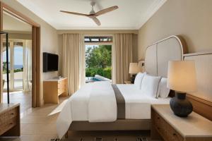 a bedroom with a large white bed and a television at The Westin Resort, Costa Navarino in Romanós