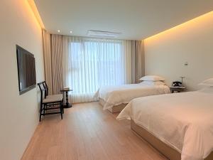 a hotel room with two beds and a television at 제주 신성의 숲 웰니스 호텔 in Haean