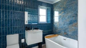 a blue tiled bathroom with a toilet and a sink at 4131 Beach Drive Bliss & Flip Flop Cottage in Struisbaai +39 photos