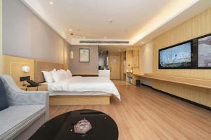 Gya Hotel Chengdu Global Center Jinchenghu Metro Station في تشنغدو: غرفة فندقية مع سرير وتلفزيون بشاشة مسطحة