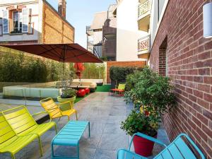 a patio with chairs and tables and an umbrella at ibis Styles Deauville Centre in Deauville