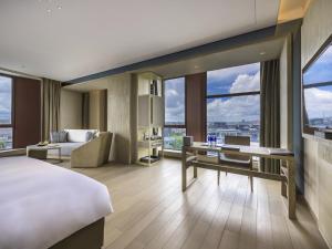 a hotel room with a bed and a desk and windows at Novotel Shanghai Clover in Shanghai