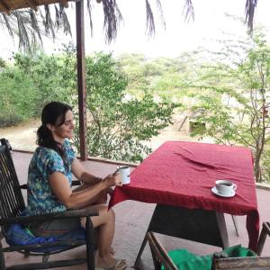 a woman sitting at a table with a cup of coffee at Wasi Center Homestay in Máncora