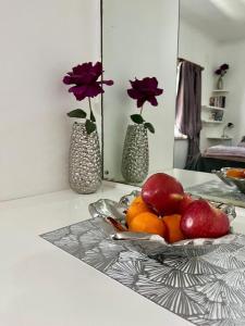 a bowl of fruit on a table with two vases at Canberra on Greenwood in Cape Town