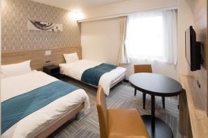 um quarto de hotel com duas camas e uma mesa em Nest Hotel Osaka Shinsaibashi em Osaka