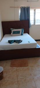 a bed with a brown headboard and a pillow on it at Villa guest house in Ndola