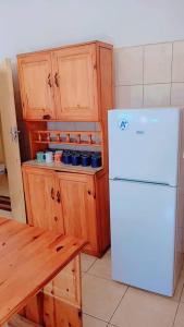 a kitchen with a white refrigerator and wooden cabinets at Villa guest house in Ndola +10 photos