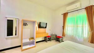 a bedroom with a bed and a tv and a window at Berlian Guest House Syari'ah in Martapura