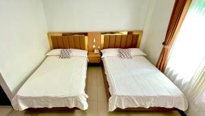 two beds in a small room with a window at Berlian Guest House Syari'ah in Martapura
