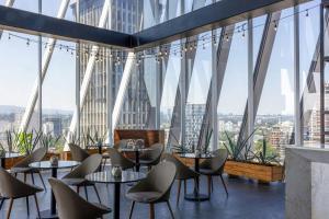 ein Restaurant mit Tischen und Stühlen und großen Fenstern in der Unterkunft AC Hotel by Marriott Guadalajara Mexico in Guadalajara