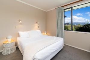 a bedroom with a white bed and a large window at Beacon Point Lakeview Escape - Spacious - Stylish in Wanaka