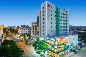 a tall white building on a city street at night at Borrman Hotel Wanning Wenming Road High-speed Railway Station in Wanning