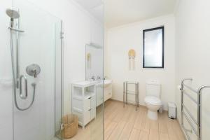 a white bathroom with a shower and a toilet at Beacon Point Lakeview Escape - Spacious - Stylish in Wanaka