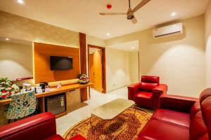 Grand Royal Residency في Pala: غرفة معيشة بأثاث احمر وتلفزيون