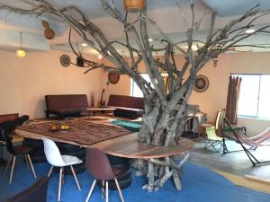 a table with a tree in the middle of a room at Guest House & Cafe Ohana in Imabari