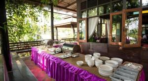 a table with a purple table cloth and a room with a mirror at De Bua Valley in Ban Kom
