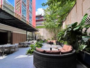 an outdoor patio with tables and chairs and plants at H-hotel Riverside in Chengdu
