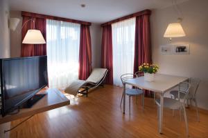 a living room with a television and a table with chairs at AlbaResidence Masera26 in Alba