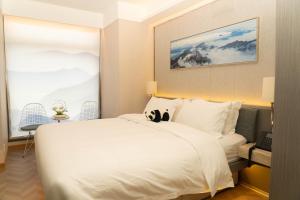 a bedroom with a white bed with a cat sitting on it at H-hotel Riverside in Chengdu +41 photos