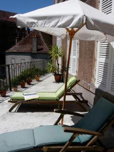 una silla y una sombrilla en un patio con cama en La Maison Févret en Semur-en-Auxois