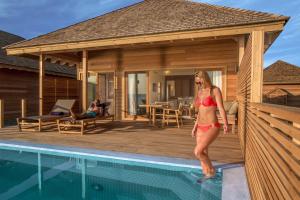 a woman in a red bikini standing next to a swimming pool at Hurawalhi Island Resort in Kuredu