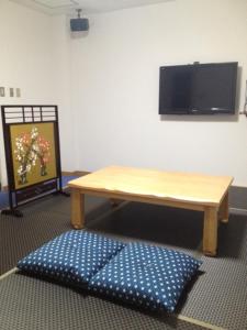 a table and a bench in a room with a tv at Sea Queen Kainan in Kainan