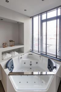 a large white bath tub in a room with a window at Timeless luxury suites & SPA in Thessaloniki