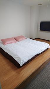 a bed with white sheets and pink pillows in a room at Sea Queen Kainan in Kainan +7 photos