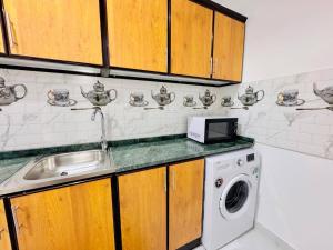 a kitchen with a sink and a washing machine at Fully Furnished Studio Near Exibition Center Abu Dhabi in Abu Dhabi +5 photos