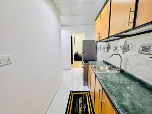 a kitchen with a sink and a refrigerator at Fully Furnished Studio Near Exibition Center Abu Dhabi in Abu Dhabi