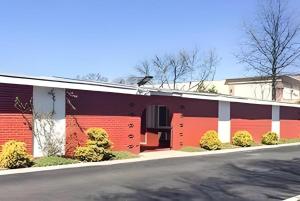 a building with red and white doors and a street at Travelodge by Wyndham Bay Shore Long Island in Bay Shore