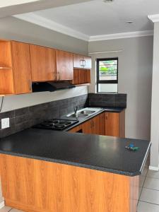 a kitchen with wooden cabinets and a black counter top at Da Silva Apartment in George