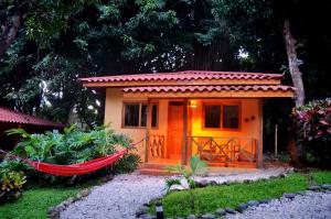 Esencia Hotel and Villas في شاطئ سانتا تيريزا: منزل صغير مع أرجوحة في حديقة