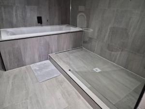 a bathroom with a shower and a tub and a sink at Coastal Cove in Cape Town