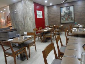a dining room with wooden tables and chairs at Royal Park Hotel Dockyard in Mumbai