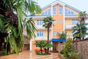 um edifício com palmeiras em frente em Mini hotel Delphin em Adler
