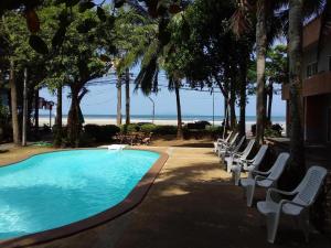 a swimming pool with white lounge chairs and the beach at Jinta Hotel Nathon Beach in Nathon