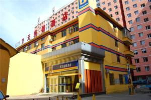 a large yellow building with colorful trim in a city at 7 Days Inn Hohhot Hailiang Xinhua Square Metro Station in Hohhot
