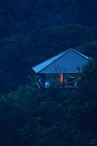 ein Haus mit einem Dach auf einem Hügel in der Unterkunft The IBNII - Eco Luxury Resort in Madikeri