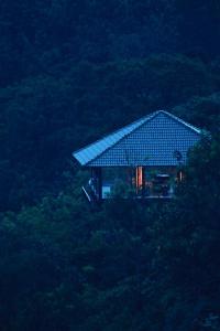 a house with a roof on top of a hill at The IBNII - Eco Luxury Resort in Madikeri