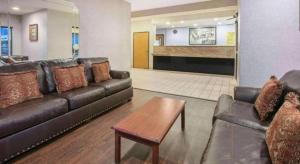 a living room with a leather couch and a table at Super 8 By Wyndham Garland North Dallas Area in White Rock +12 photos