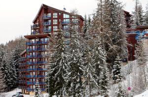 a building with snow covered trees in front of it at Les Arcs 1800 Ruitor in Arc 1800