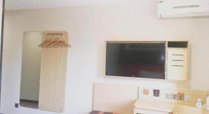 a kitchen with a microwave and a television on the wall at 7 Days Premium JiNan Jingshi Road Qilu Children's Hospital Exhibition Center in Jinan