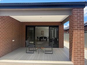 Un patio con una mesa y sillas en una pared de ladrillos. en Stunning 4 X Bed Holiday Home In Kalkallo!, en Kalkallo