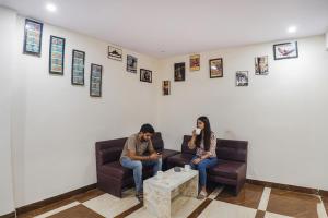 a man and woman sitting on a couch in a room at FabHotel The Pannis in Bhopal